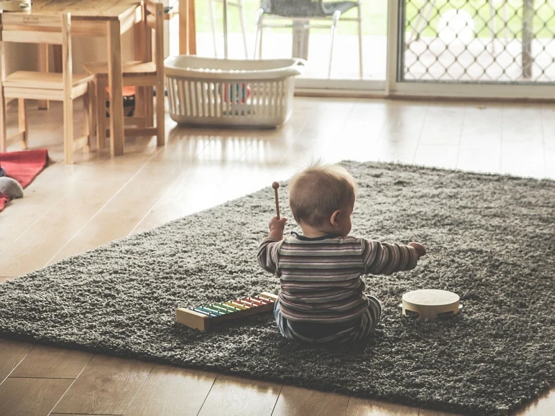 ein Baby sitzt auf einem Teppich vor einem Glockenspiel und einem Tamburin
